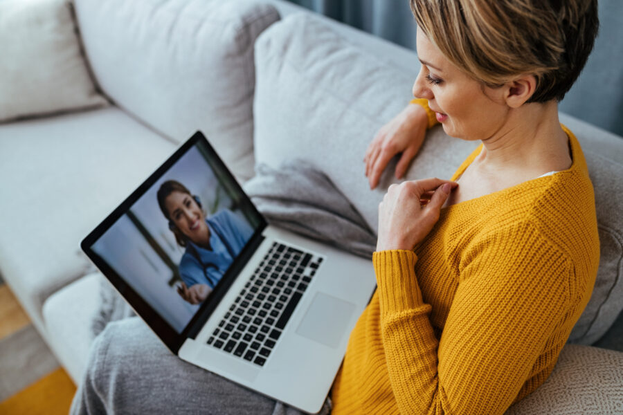Woman using laptop and telehealth video call with her doctor while at home